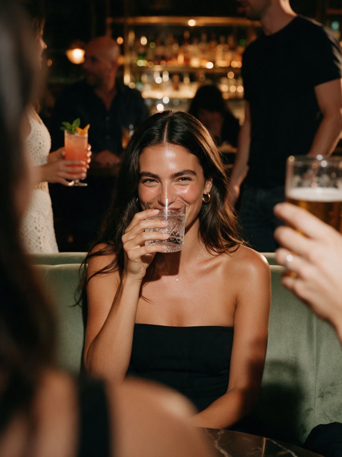 Mulher sorrindo com um drink no bar